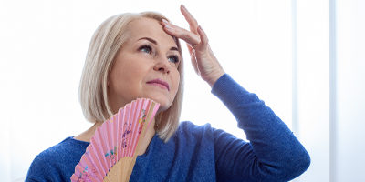 A woman with a foldable fan trying to cool herself down.