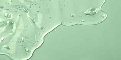 A light green background with a serum texture spilled on top.