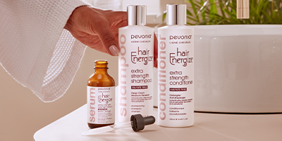Woman reaching for Pevonia Hair Energize products near her sink.