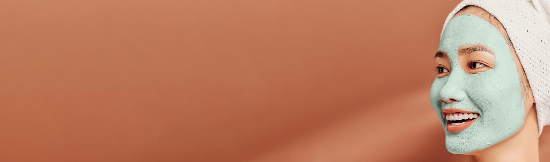 A woman with a skincare mask and her hair wrapped in a towel.