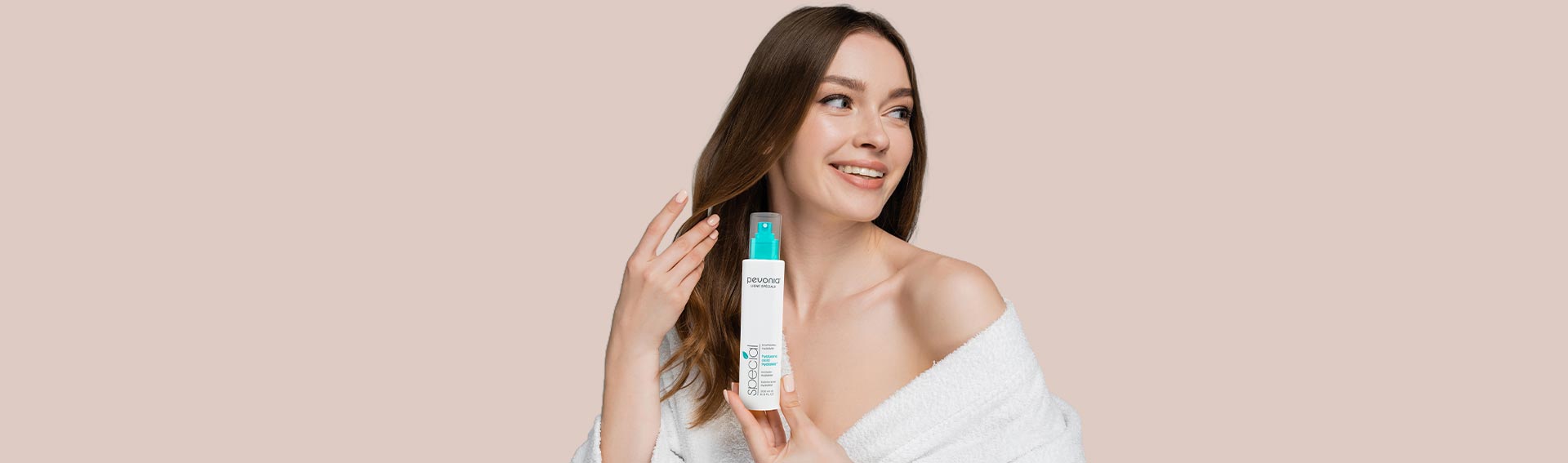 Woman smiling while holding Pevonia's Hyaluronic Acid HydraMist.